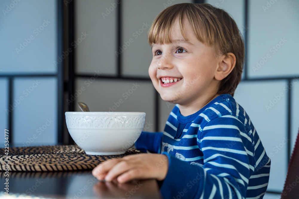 Cute little child having lunch at home. Toddler sitting at the table, tasting soup in a bowl. Happy smiling boy eating healthy domestic food. Cute little child having lunch at home. Toddler sitting at the table, tasting soup in a bowl. Happy smiling boy eating healthy domestic food.