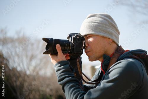 一眼レフカメラで写真を撮る男性 © hakase420