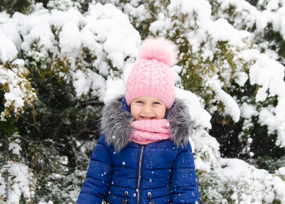 A girl in a pink hat plays with snow. Holidays with a child in winter A girl in a pink hat plays with snow. Holidays with a child in winter