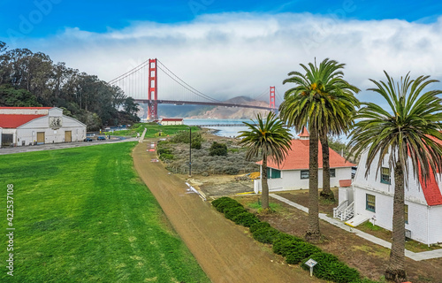 Aerial view of the Golden Gate Bridge from Presidio, against the backdrop of beautiful palm trees in San Francisco, bright sunny weather, palm trees and green grass on the lawn. photo