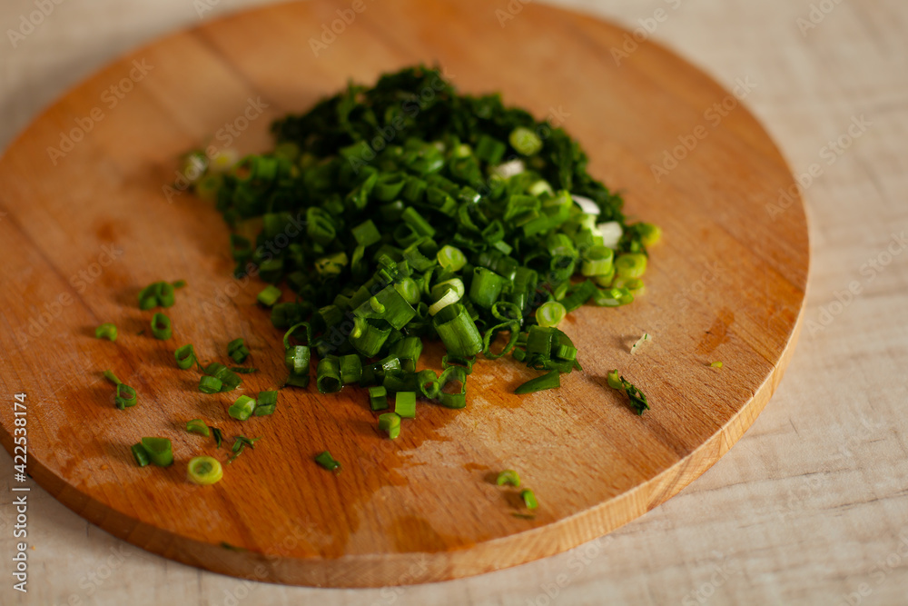 Large horizontal photo. Fresh green dill on a round wooden board. Summer time. Vitamins. Eco. Proper nutrition, healthy lifestyle. The process of cutting vegetables.