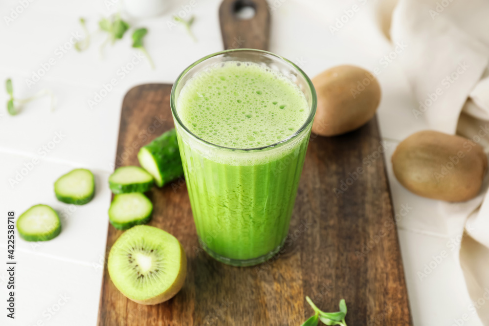 Glass of tasty green smoothie and ingredients on light background, closeup Glass of tasty green smoothie and ingredients on light background, closeup