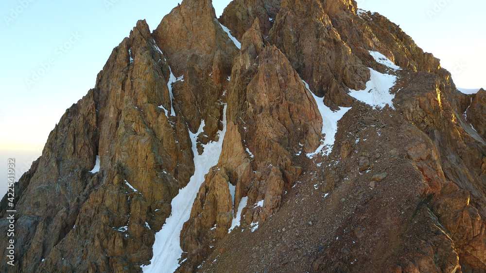 Huge snow mountains. View from the top of the drone. In places, you can see small people climbing to the top. Panorama of steep peaks and rocks, snow cornices. Mountaineering class. Extreme rest. Huge snow mountains. View from the top of the drone. In places, you can see small people climbing to the top. Panorama of steep peaks and rocks, snow cornices. Mountaineering class. Extreme rest.