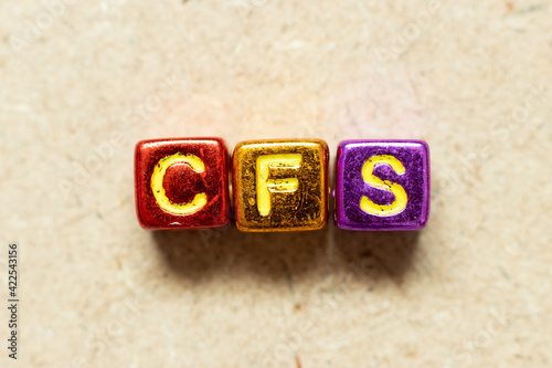 Metallic color alphabet letter block in word CFS (Abbreviation of Container Freight Station, Certified fund specialist or Chronic fatigue syndrome) on wood background photo