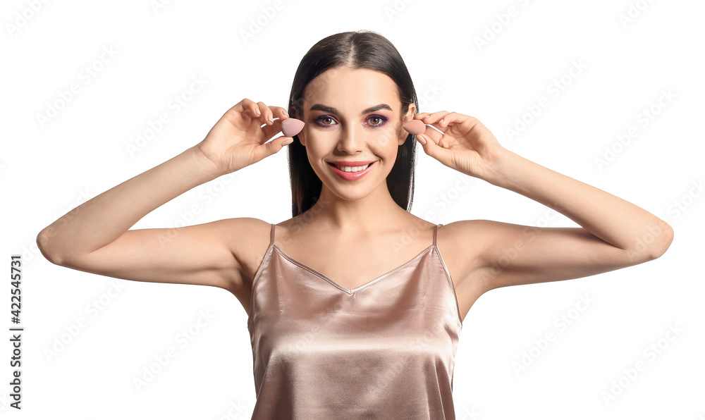 Beautiful young woman with makeup sponges on white background Beautiful young woman with makeup sponges on white background