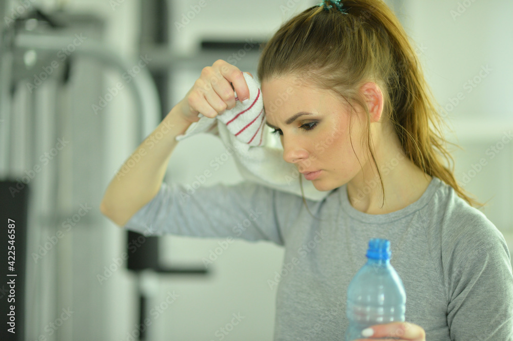 Sporty young woman with water after training in gym Sporty young woman with water after training in gym
