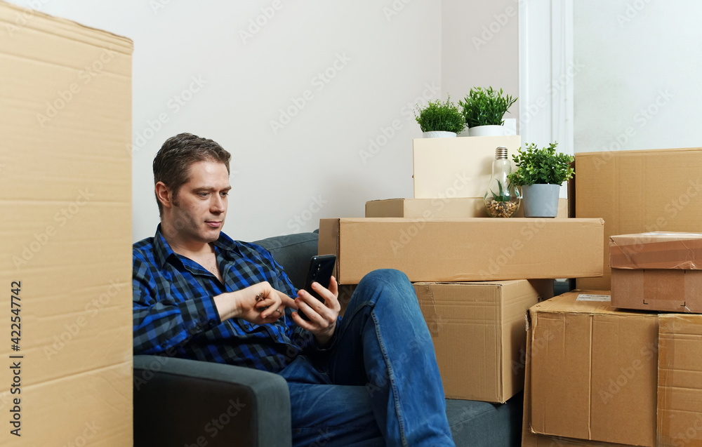Man with smartphone in new apartment.