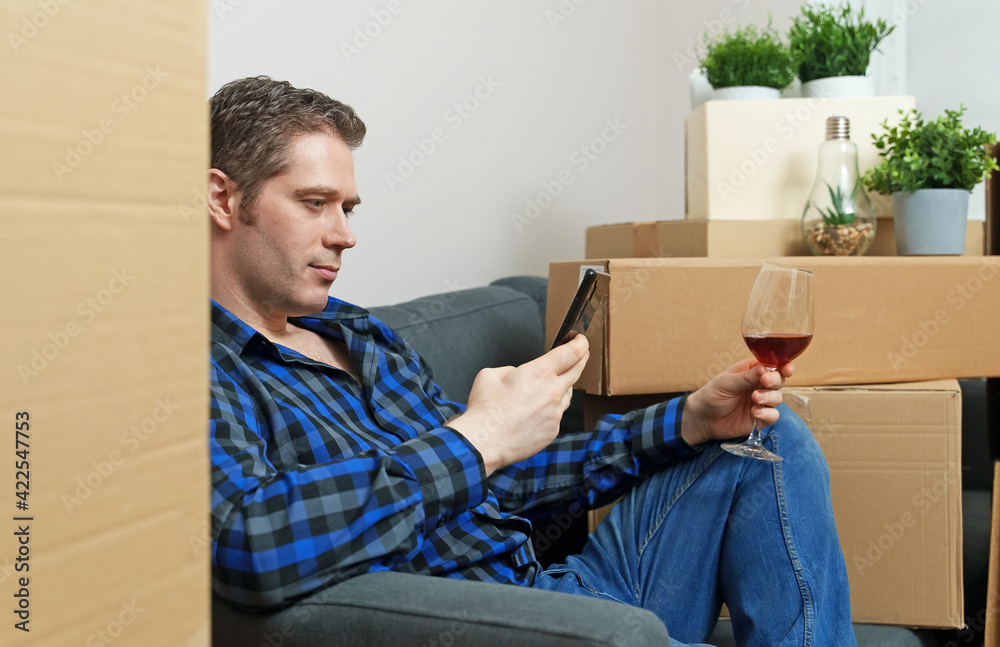 Man with smartphone and glass of wine in new apartment. Man with smartphone and glass of wine in new apartment.