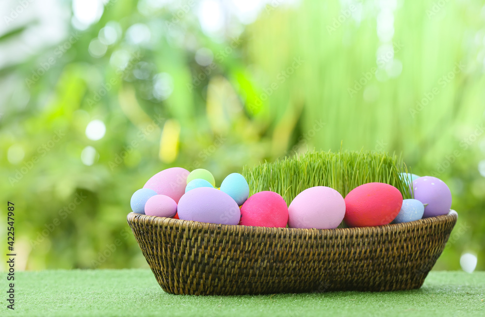Basket with beautiful Easter eggs on grass outdoors Basket with beautiful Easter eggs on grass outdoors