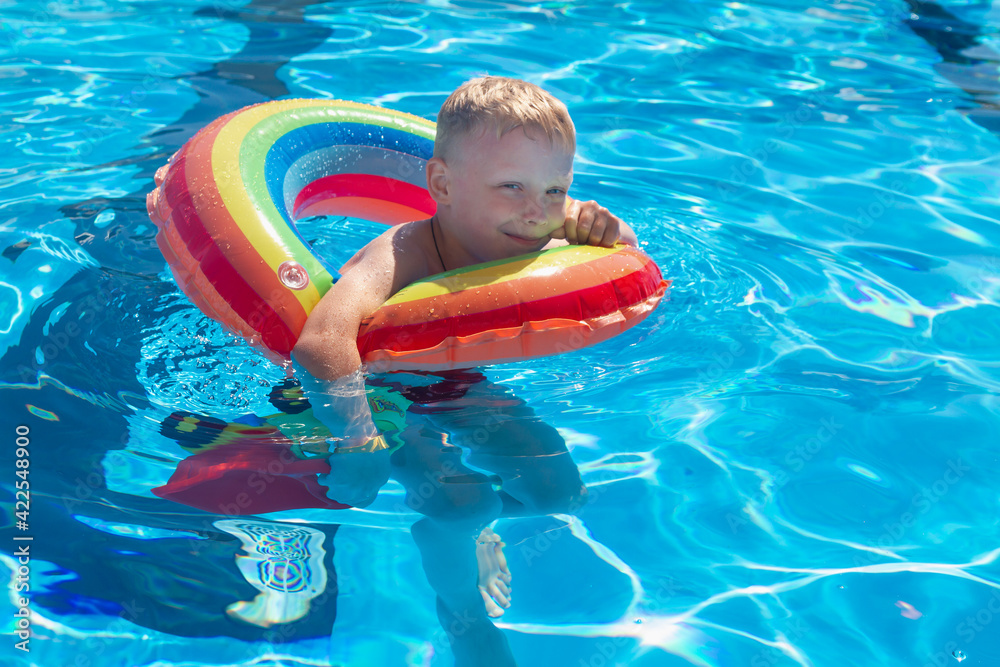 A child swims in a pool with blue water on a colorful inflatable circle