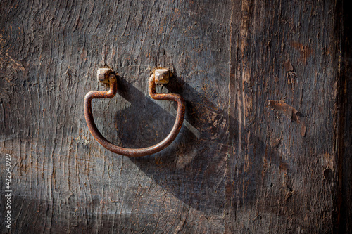 Rusted, antique door knocker on old weathered door in Sicily.CR2