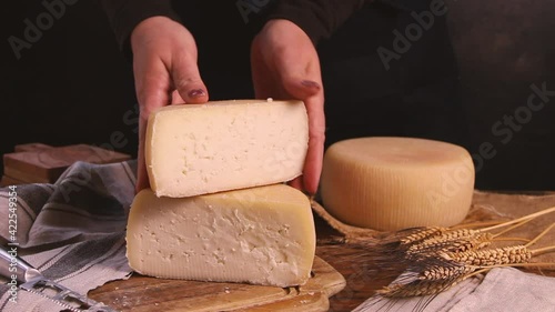 Women hands showing fresh homemade cheese on a wooden board with a cheese knife close up