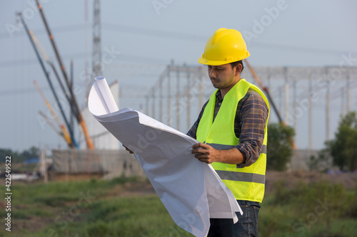 Asian construction workers check drawings plan blueprint at construction site