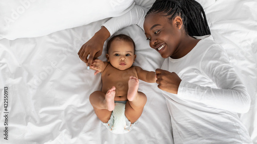 African American mom lying in bed with her cute infant