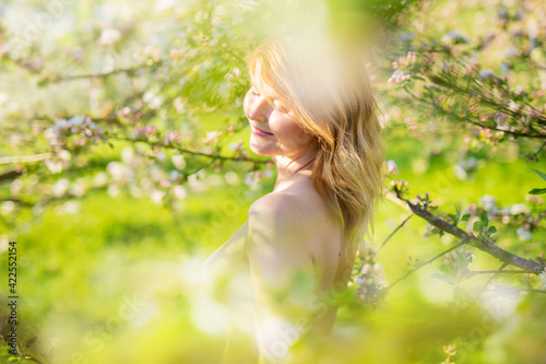 Moody portrait of middle aged woman in spring blossom at sunrise