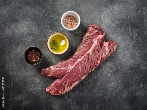 Raw hanging tender or onglet steak of beef on grey background with salt, pepper and olive oil. photo