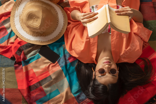 A STYLISH YOUNG WOMAN WEARING GOGGLES READING A BOOK	