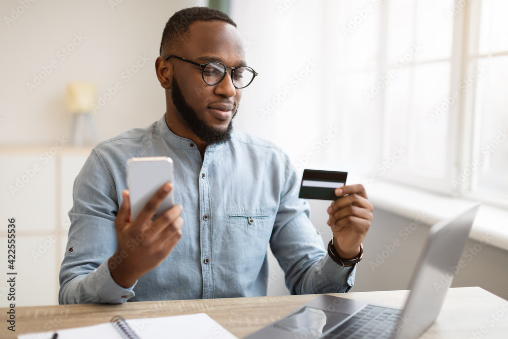 African American Businessman Using Cellphone And Credit Card In Office African American Businessman Using Cellphone And Credit Card In Office