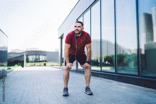 Confident sportsman resting after training on street
