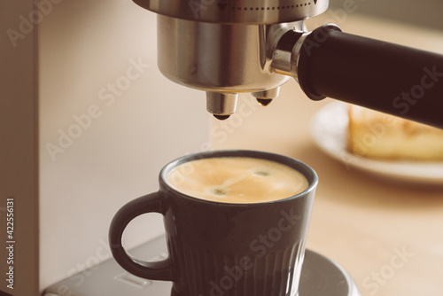 Morning ritual at breakfast with pouring coffee from coffee machine  making espresso from coffee maker to little mug. Authentic everyday routine tasks with hot drink. Soft focus