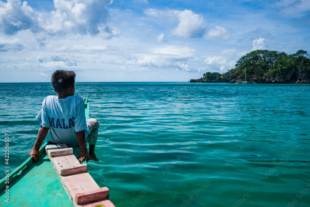 A local boy on a boat on the shore of Boracay, Philippines looking out on the horizon.
