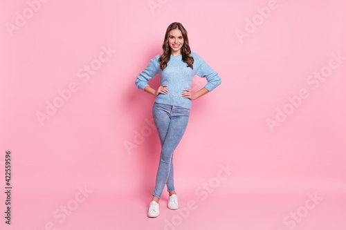 Full size photo of young happy cheerful good mood smiling girl wear blue sweater and jeans isolated on pink color background