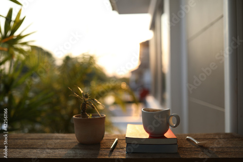 Coffee cup and notebook and pencil with plant pot on brown wooden table at outdoor