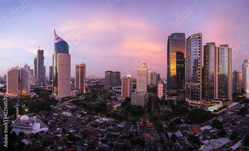 Stunning sunset over Jakarta skyline where modern office and condominium towers contrasts with traditional village  called Kampung  in Indonesia capital city