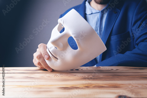 Obraz na plátně Businessman holding white mask in his hand
