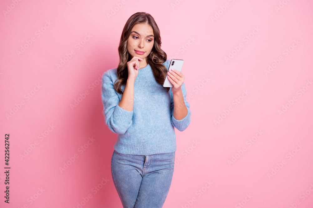 Photo of smart lady hold telephone finger chin look screen think wear blue sweater isolated pink background Photo of smart lady hold telephone finger chin look screen think wear blue sweater isolated pink background