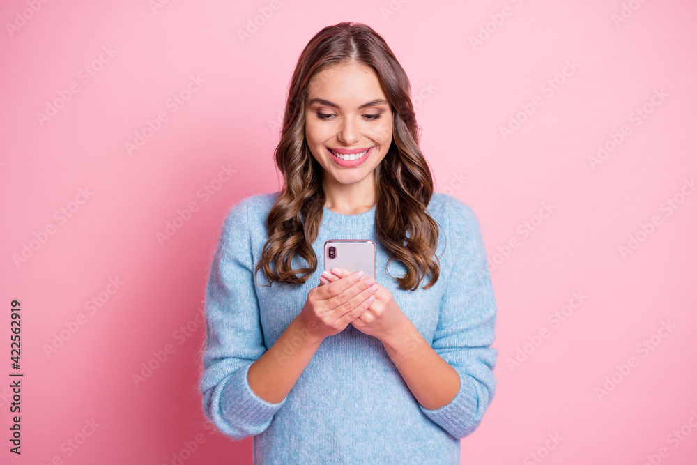 Photo of cheerful lady hold telephone look screen toothy shiny smile wear blue pullover isolated pink background Photo of cheerful lady hold telephone look screen toothy shiny smile wear blue pullover isolated pink background