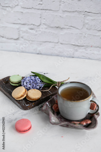 Breakfast tea with macaroons on a wooden background with a hyacinth flower and a beautiful saucer. Vertical orientation
