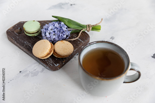 Breakfast tea with macaroons on a wooden background with a hyacinth flower and a beautiful saucer. horizontal orientation
