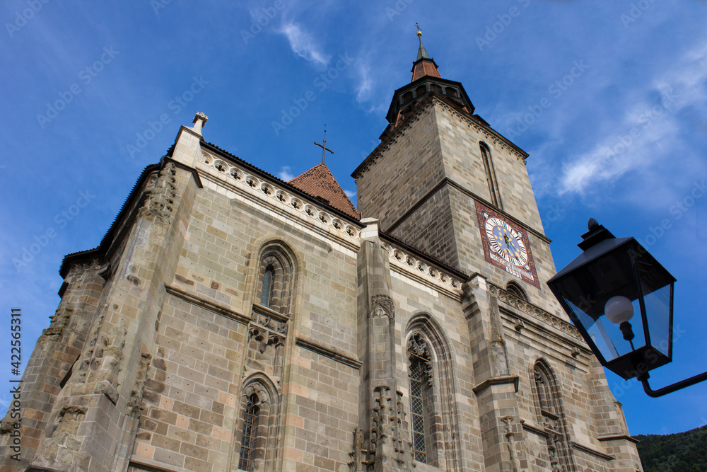 Low angle view of Black Church clock tower from Brasov, Romania with clear blue sky