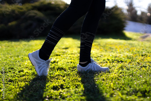 Young woman running on the field in the morning. Active person outdoor. Close-up on shoe
