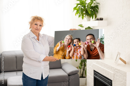 Wallpaper Mural A happy blonde woman is holding a large wall canvas portrait of her family with young children. Torontodigital.ca