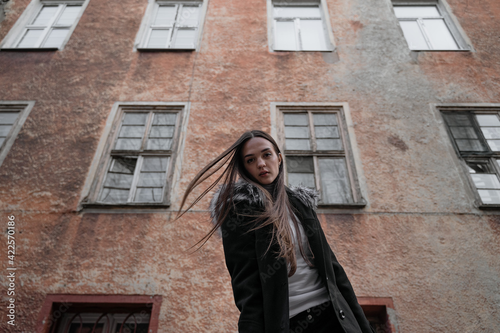 girl a stands against the background of an old house