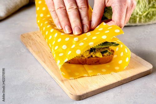 Woman hands wrapping a healthy sandwich in beeswax food wrap and cotton bag