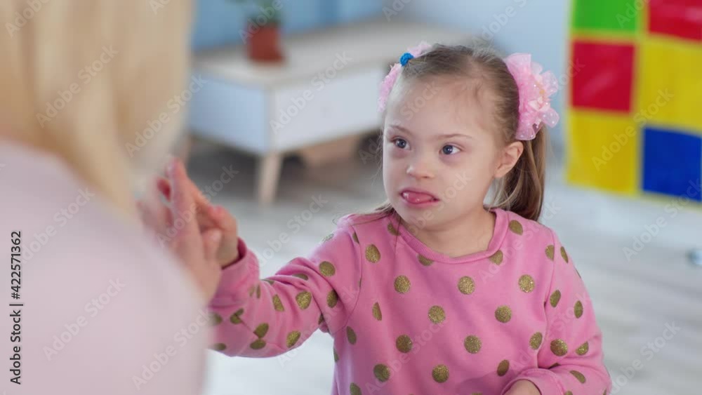 girl with down syndrome giving five hands to her teacher during class girl with down syndrome giving five hands to her teacher during class