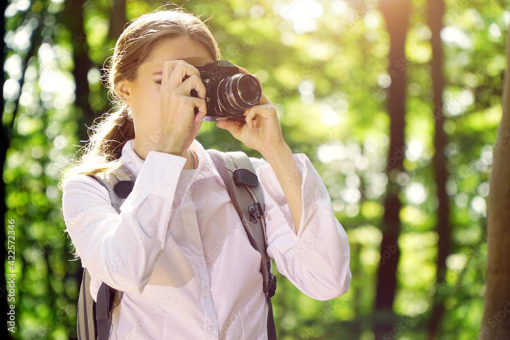 Young woman hiking in forest and taking pictures with old camera Young woman hiking in forest and taking pictures with old camera