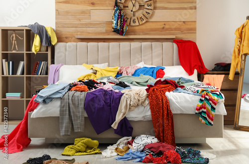 Photography Pile of clothes on bed in messy room. Fast fashion concept
