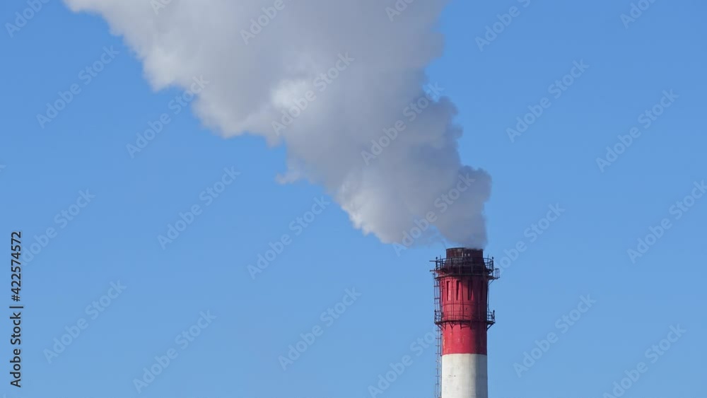 Chimney of power plant on blue sky white vapor from red tube. Smoke clouds coming out of factory chimney. Air pollution and global warming caused by old industrial power plant Chimney of power plant on blue sky white vapor from red tube. Smoke clouds coming out of factory chimney. Air pollution and global warming caused by old industrial power plant