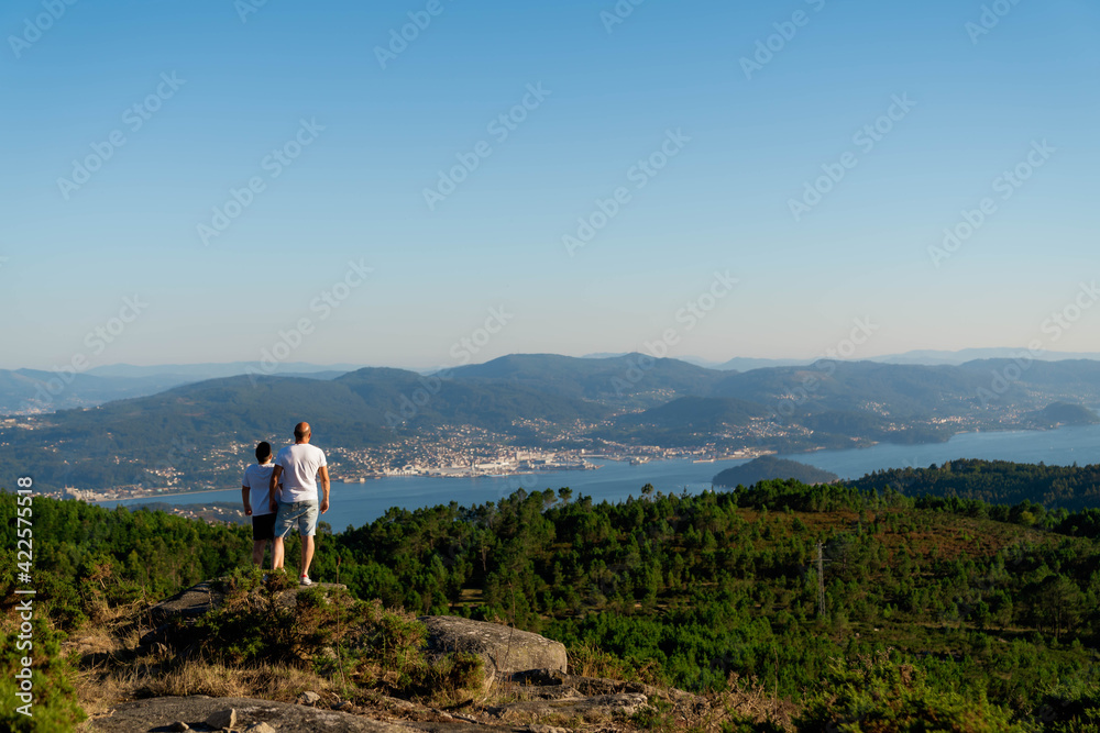 Hombre y niño mirando el mar desde la montaña y el bosque