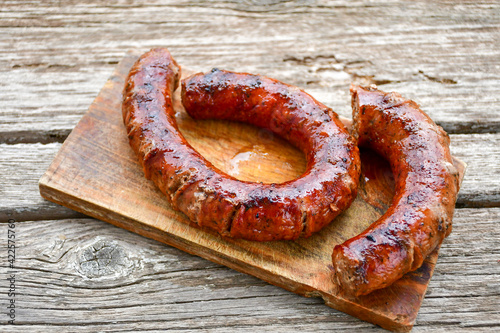 Grilled pork sausages on wooden board outdoors. Grilling food, bbq, barbecue, picnic