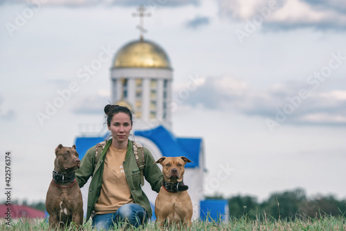 Foto Young beautiful dark-haired girl with pit bull terriers in the field
