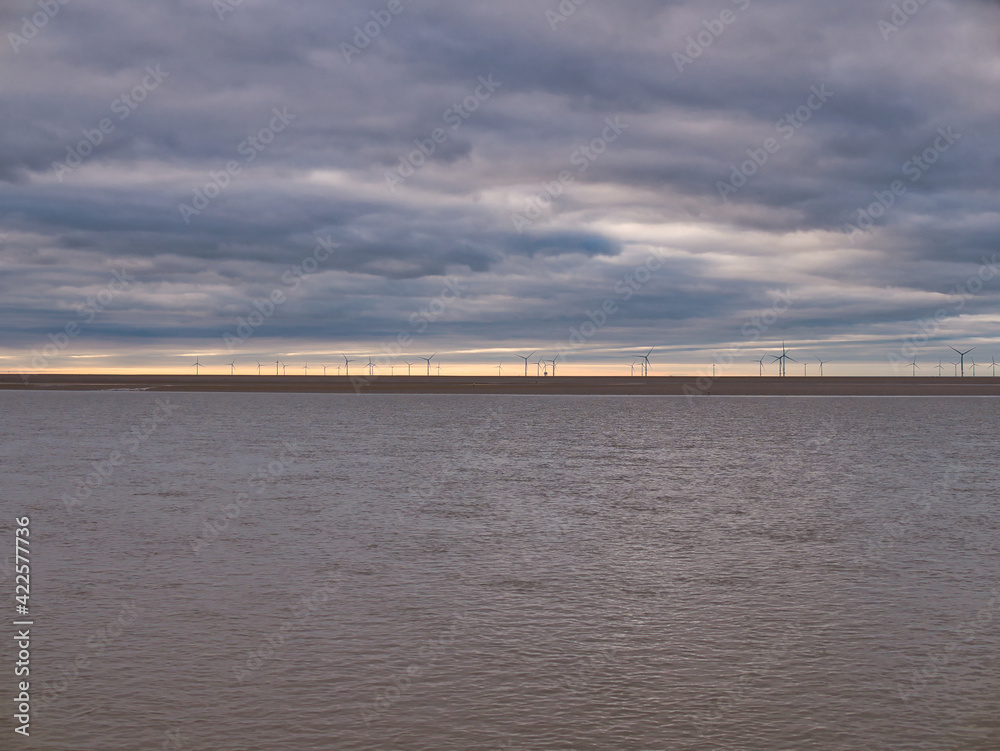 Offshore wind turbines off Wirral in the Mersey Estuary in the north west of the UK. The turbines are on the Burbo Bank and are some of the largest in the world .