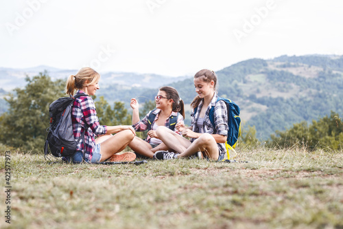 Mother hiking with her daughters.They taking a break and resting after long walk.