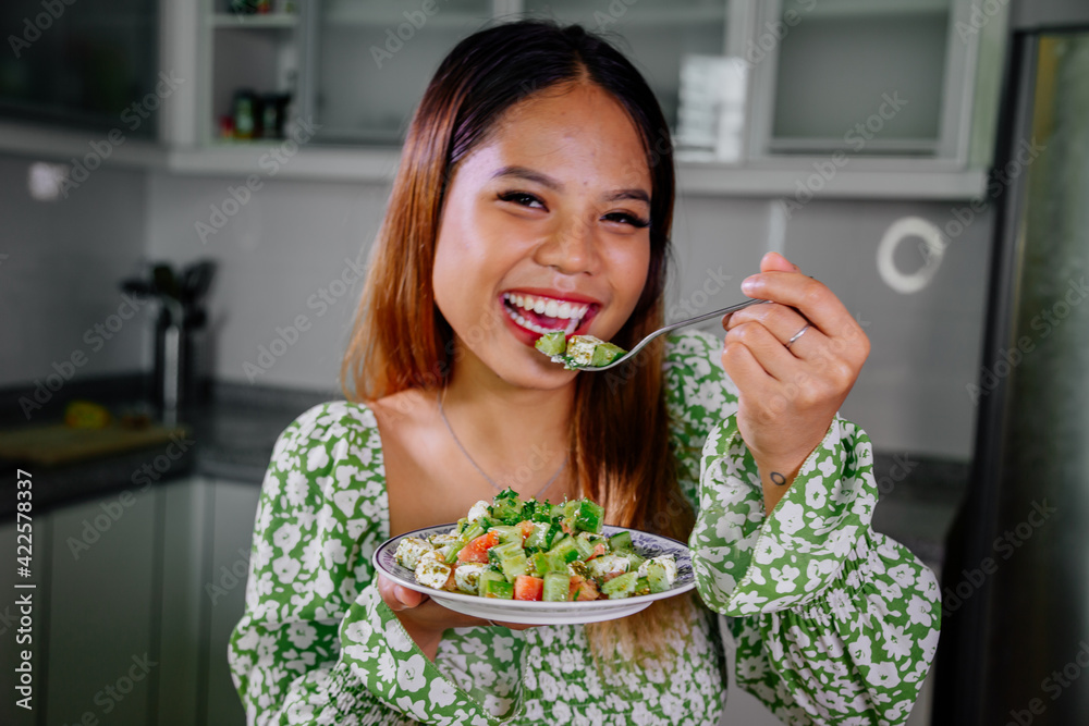beautiful young asian woman eating healthy mediterranean food. smiling happy girl eating greek salad beautiful young asian woman eating healthy mediterranean food. smiling happy girl eating greek salad