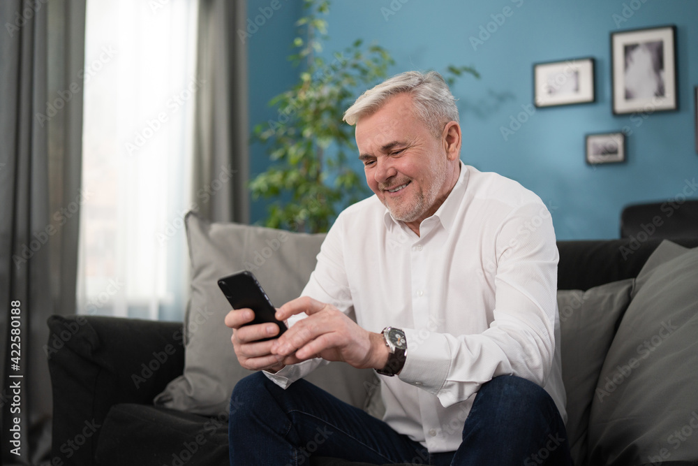 Smiling senior old man talking using cell phone computer modern tech at home on weekend lifestyle, happy elderly grandfather doing internet shopping choose sale offers Smiling senior old man talking using cell phone computer modern tech at home on weekend lifestyle, happy elderly grandfather doing internet shopping choose sale offers
