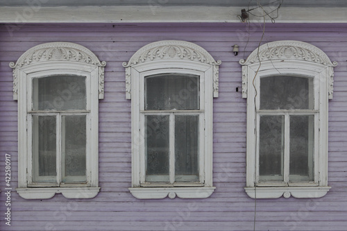 Ornamental carved windows, frames on lilac traditional national old wooden rural house in Gorodets city, Russia. Russian folk style in architecture. Gorodets architectural monument, Gorodets landmark photo